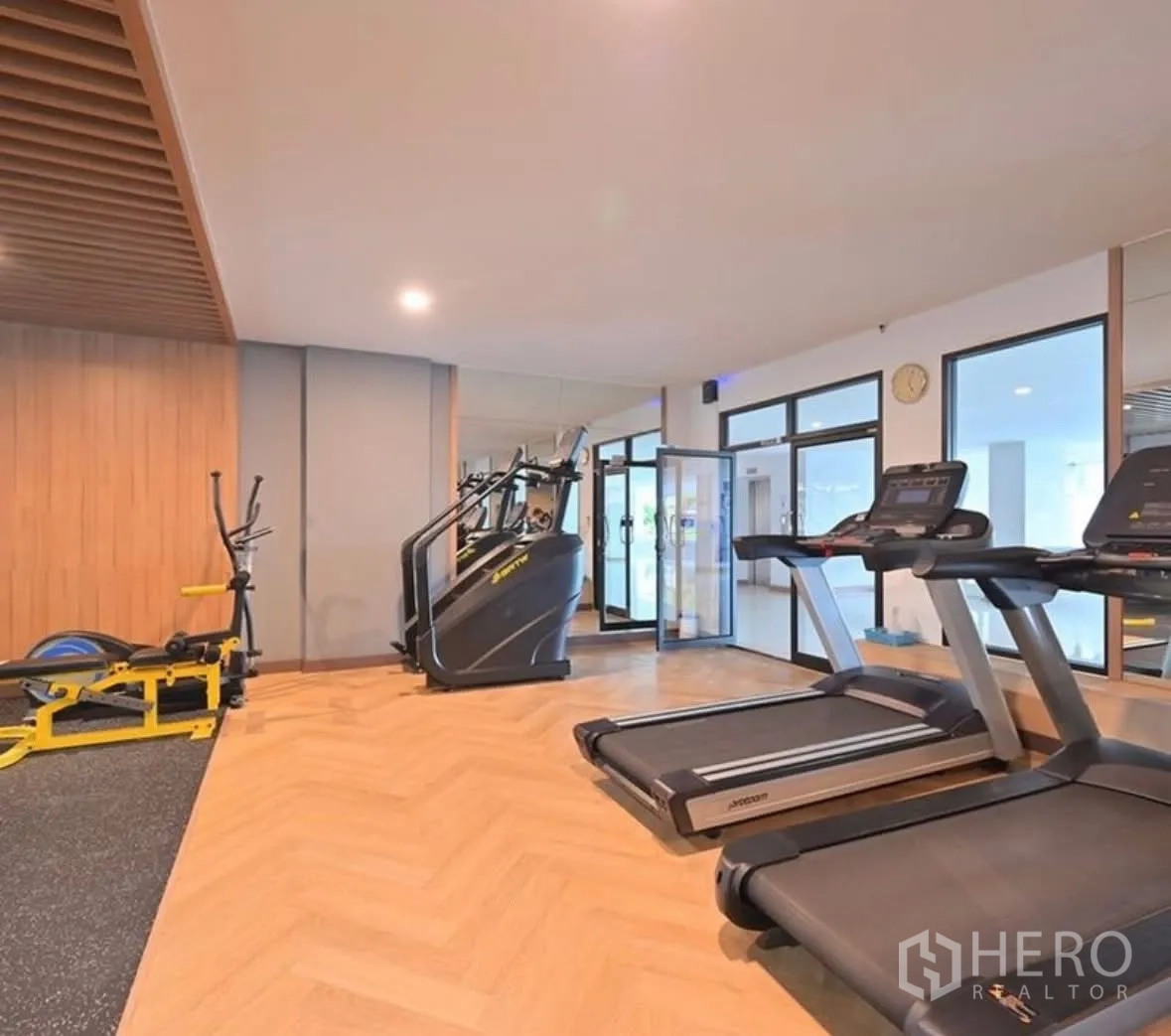 Condominium for rent or sale in Watthana, Bangkok - Gym area with treadmills and cardio machines on wood flooring.