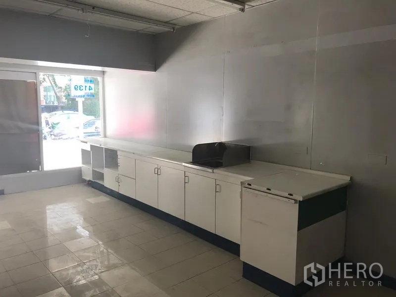 零售空间 出租在Watthana, Bangkok - 店铺前区配长条内置操作台和橱柜，旁有大幅展示窗。