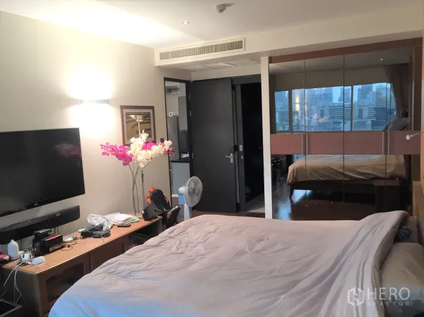 คอนโด ขายในPathum Wan, Bangkok - ห้องนอนหลักพร้อมทีวีติดผนังและตู้เสื้อผ้าบานกระจก