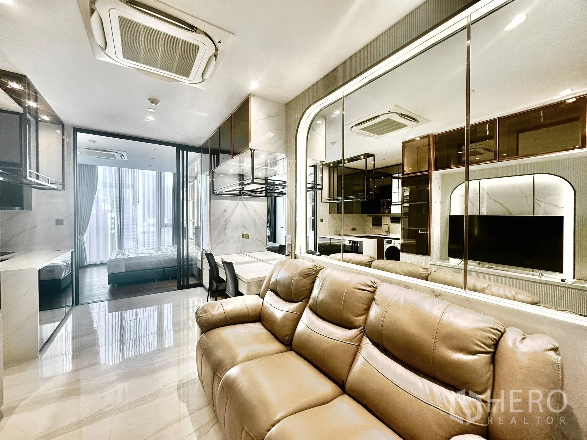 คอนโด for rent in Sathon, Bangkok - พื้นที่นั่งเล่นมีโซฟาหนังปรับเอนได้หันสู่ผนังกระจกและครัวแบบเปิด