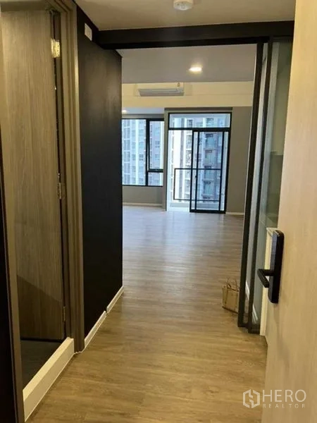 Condominium for sale in Huai Khwang, Bangkok - Hallway opening to a bright living room with balcony and city view.
