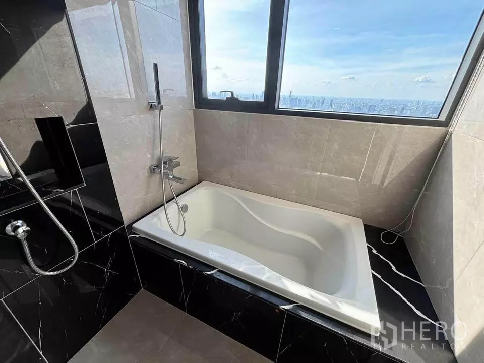 公寓 出租在Huai Khwang, Bangkok - 浴室设观景浴缸，窗外为城市天际线。