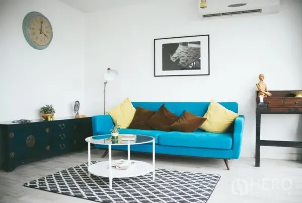 公寓 出售在Phra Khanong, Bangkok - 现代客厅，蓝色沙发、圆形茶几、墙上装饰画与空调。