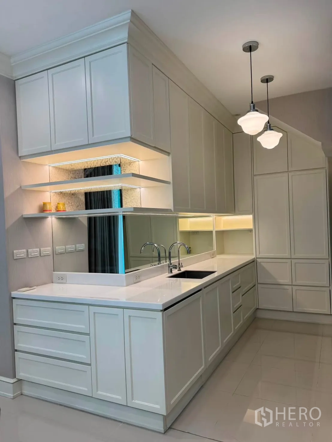 Townhouse for rent in Lat Phrao, Bangkok - Bright white built-in kitchen with double sinks, shelving and pendant lights.