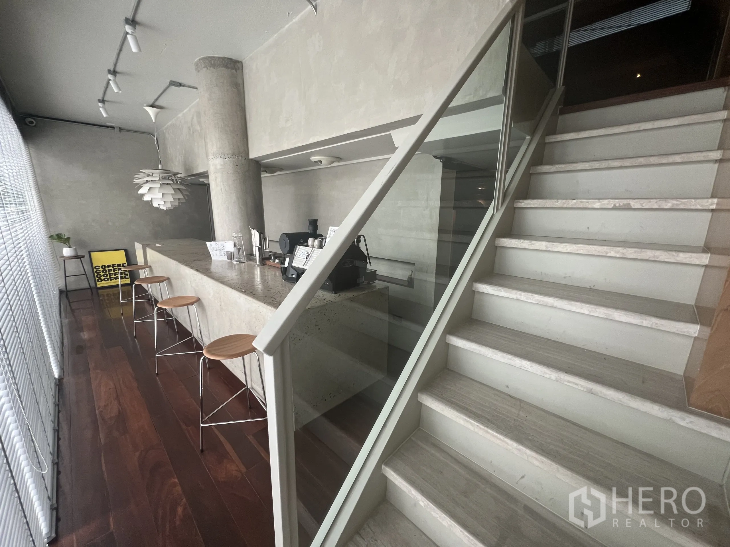 零售空间 出租在Watthana, Bangkok - 混凝土吧台旁的玻璃栏杆楼梯与轨道灯。
