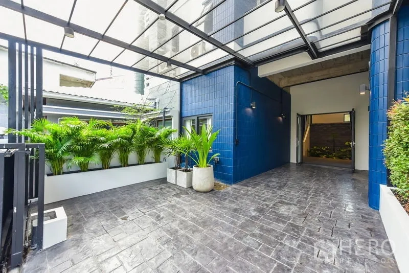Home Office for rent or sale - Covered carport and entrance with blue tile facade and tropical plants.