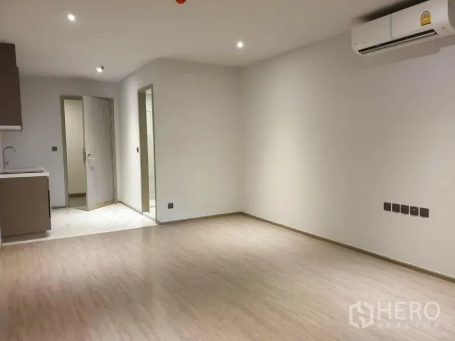 Condominium for sale in Watthana, Bangkok - Spacious open living area facing the pantry kitchen and bathroom doorway with AC installed.