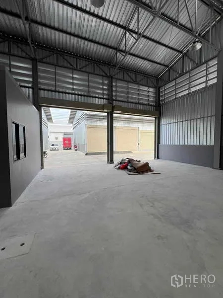 Warehouse for rent in Phra Samut Chedi, Samut Prakan - Open-plan warehouse looking out to the yard through large door openings, ready for loading.