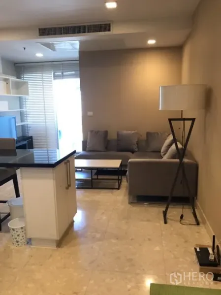 คอนโด ให้เช่าในKhlong Toei, Bangkok - ห้องรับแขกแบบโอเพ่นแปลน โซฟาเข้ามุม โคมไฟยืน และประตูกระจกออกระเบียง