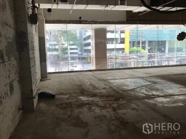 零售空间 出租在Watthana, Bangkok - 毛坯零售铺面，整面落地玻璃临街，裸露天花与水泥地面，位于曼谷瓦他那区。