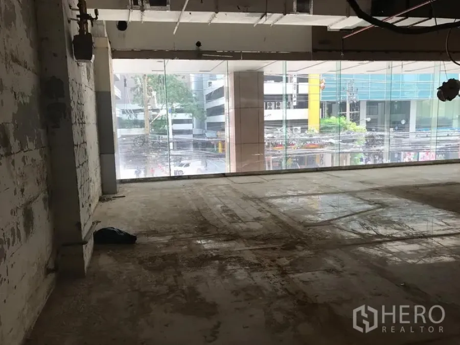 零售空间 出租在Watthana, Bangkok - 毛坯零售铺面，整面落地玻璃临街，裸露天花与水泥地面，位于曼谷瓦他那区。