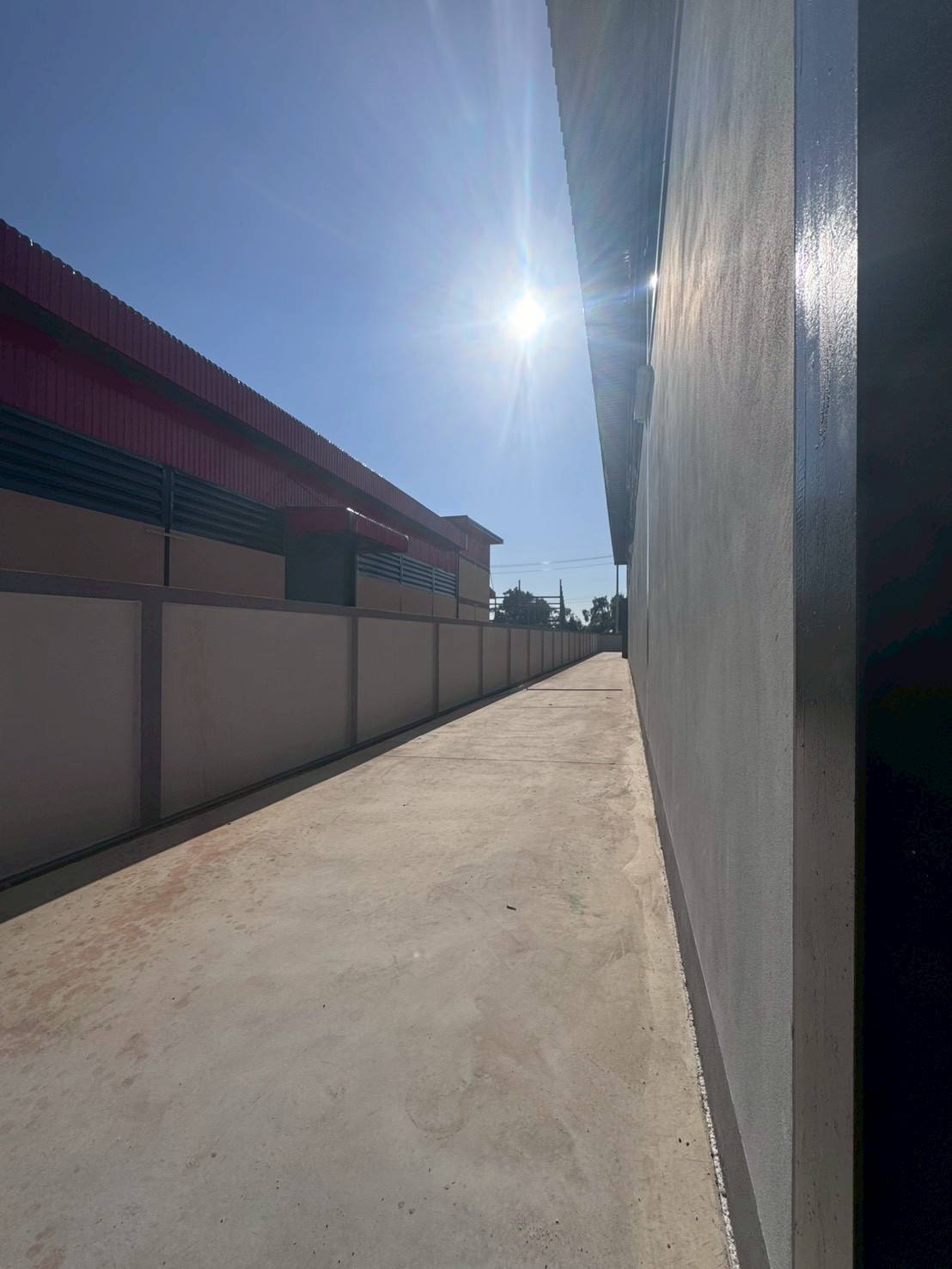 工厂 出售在Mueang Samut Sakhon, Samut Sakhon - 建筑侧边通道与围墙，阳光照射的混凝土路面。