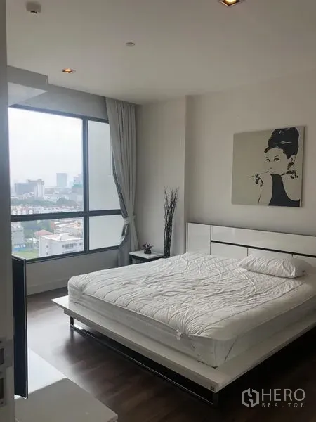 Condominium for rent or sale in Phra Khanong, Bangkok - Master bedroom with a large window and city views, white platform bed and neutral decor.