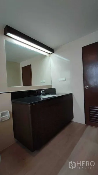 คอนโด ให้เช่าในKhlong Toei, Bangkok - มุมอ่างล้างหน้าพร้อมกระจกยาวมีไฟ และท็อปสีเข้มในห้องน้ำคอนโด