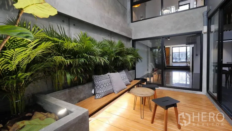 Townhouse for rent in Khlong Toei, Bangkok - Courtyard lounge with built-in planter, tropical foliage and wood seating.