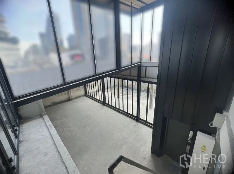 零售空间 出租在Watthana, Bangkok - 楼梯前室，半透明玻璃围护与黑色扶手，可见城市景观