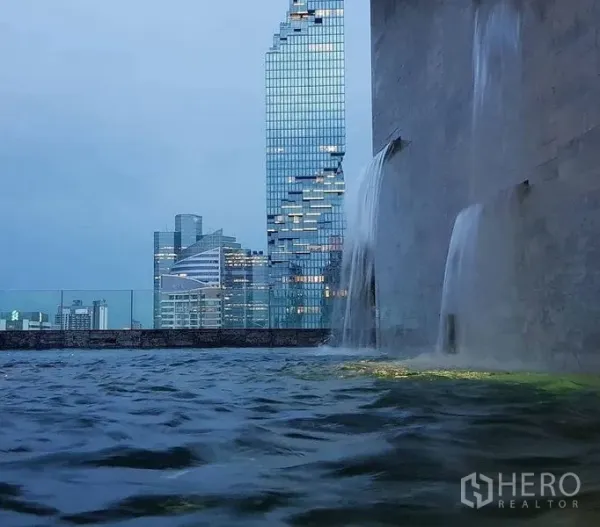 公寓 出售在Bang Rak, Bangkok - 屋顶无边泳池与瀑布景观，远眺城市天际线。