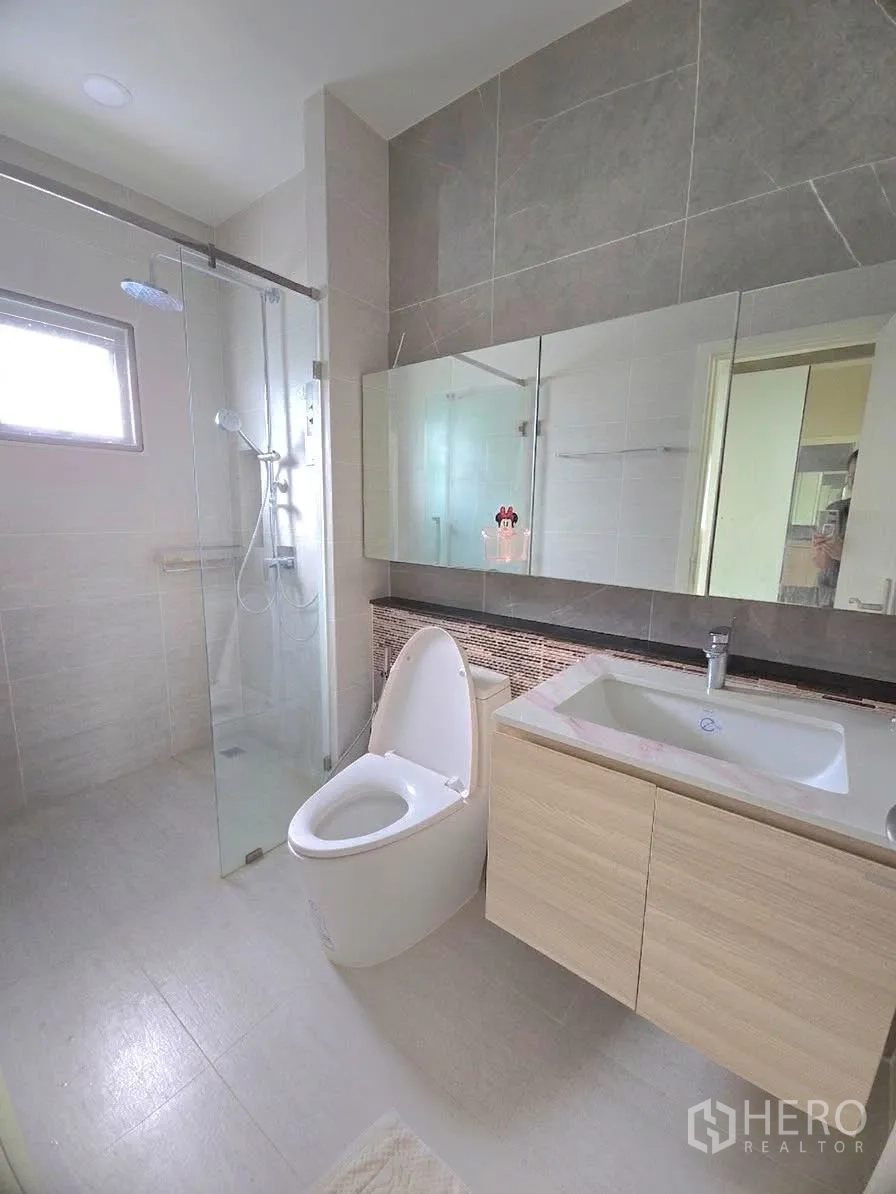 Detached House for rent in Lat Krabang, Bangkok - Modern bathroom with glass shower enclosure and wide mirror.