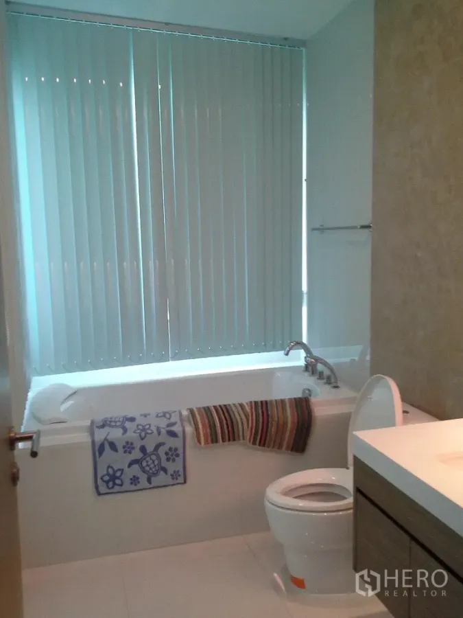 公寓 出租或出售在Khlong Toei, Bangkok - 明亮的浴室，带浴缸、垂直百叶、坐便器和洗手台。