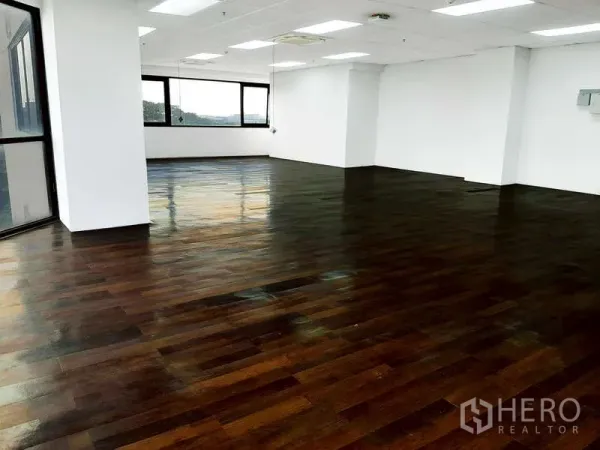 办公空间 出租 - 开放式办公室，深色木地板、白墙、嵌入式照明与大窗户。