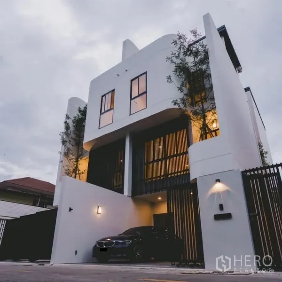 ทาวน์เฮาส์ ขายในPhra Khanong, Bangkok - ด้านนอกทาวน์โฮมร่วมสมัยแบบมีรั้ว รถจอดในโรงจอดรถในร่มยามเย็น