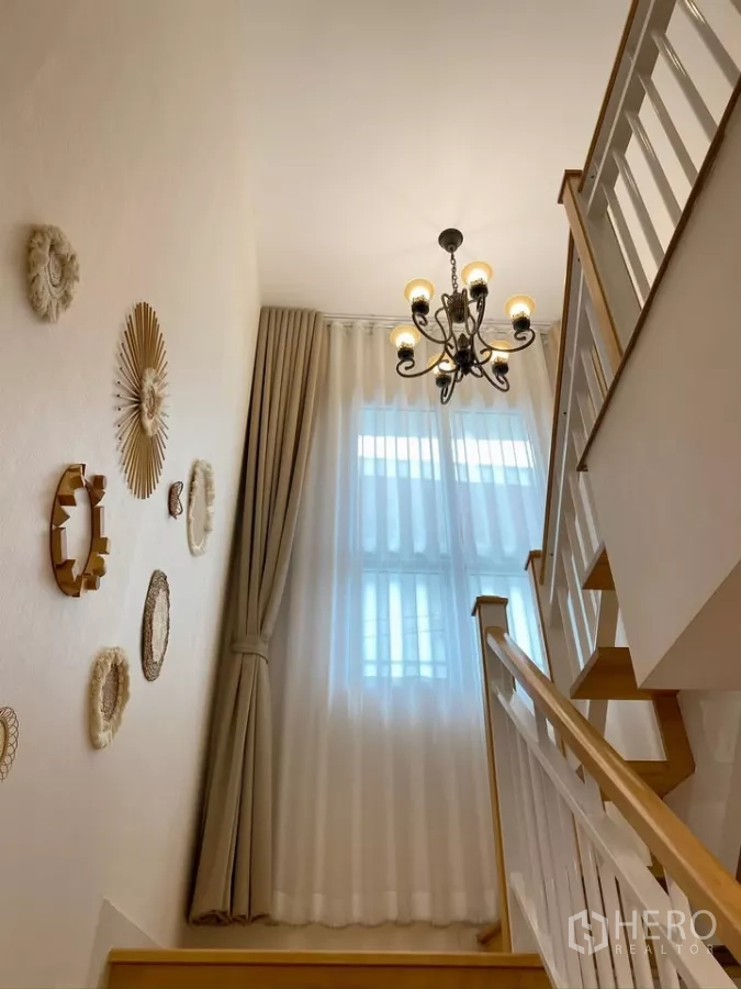 独立式住宅 出售在Sai Mai, Bangkok - 楼梯平台配枝形吊灯和高窗帘。