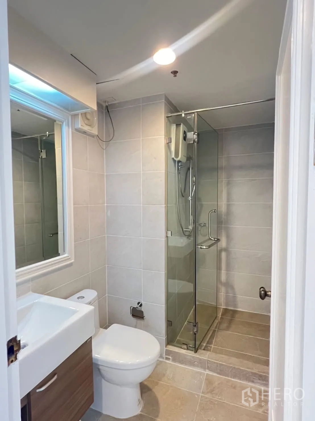 Condominium for rent in Khlong Toei, Bangkok - Compact bathroom with glass shower and modern fixtures.