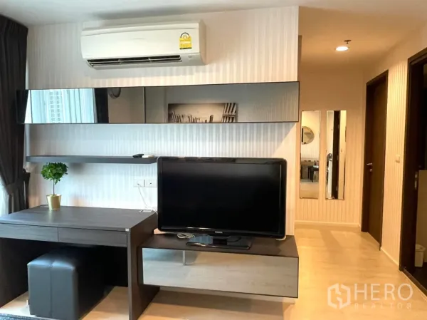 Condominium for sale in Sathon, Bangkok - Built-in media wall with floating shelves, work desk, TV and split-type air conditioner.