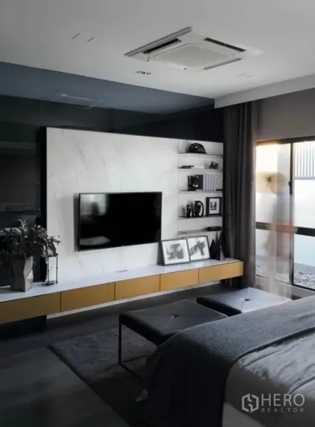 Townhouse for rent or sale in Bang Phli, Samut Prakan - Contemporary bedroom with wall-mounted TV, built-in shelves and a large window with blackout curtains.