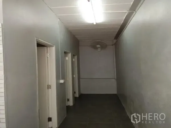 คลังสินค้า ให้เช่าในBang Phli, Samut Prakan - โถงทางเดินไปยังห้องน้ำและห้องใช้งานพนักงาน ผนังสีเทาพร้อมไฟเพดาน