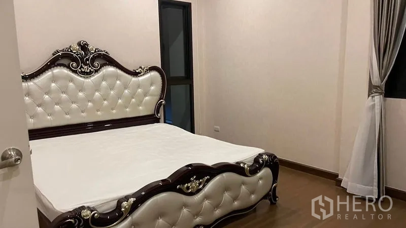 Detached House for rent or sale in Prawet, Bangkok - Guest bedroom with ornate upholstered bed and wood floors.