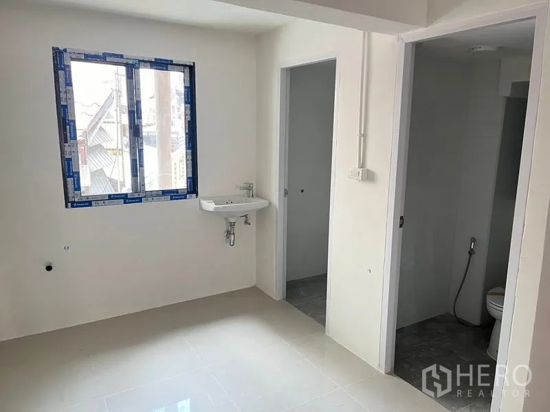 พื้นที่ขายปลีก ให้เช่า - ห้องหลังบ้านมีหน้าต่าง อ่างล้างมือแบบติดผนัง และประตูสองบานสำหรับเก็บของและห้องน้ำ