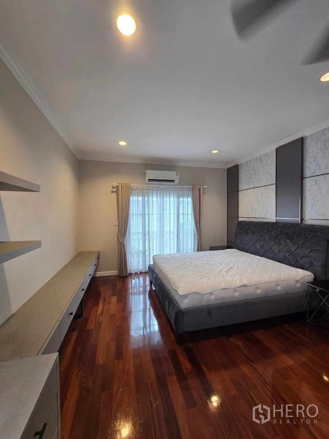 Detached House for rent in Bang Na, Bangkok - Bedroom with large bed, wood floors, and wall-mounted cabinets.