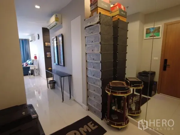 Condominium for rent in Watthana, Bangkok - Entrance hallway with tall storage, mirror wall and glossy tile floor leading to living area.