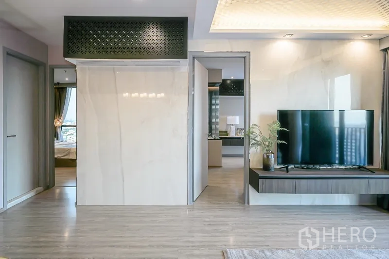 Condominium for rent in Watthana, Bangkok - Hallway and TV wall with floating console, glossy panels, and doors to bedrooms.