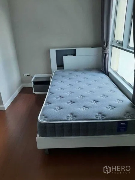 Condominium for rent or sale in Huai Khwang, Bangkok - Cozy bedroom with single bed, bedside table and large window with curtains