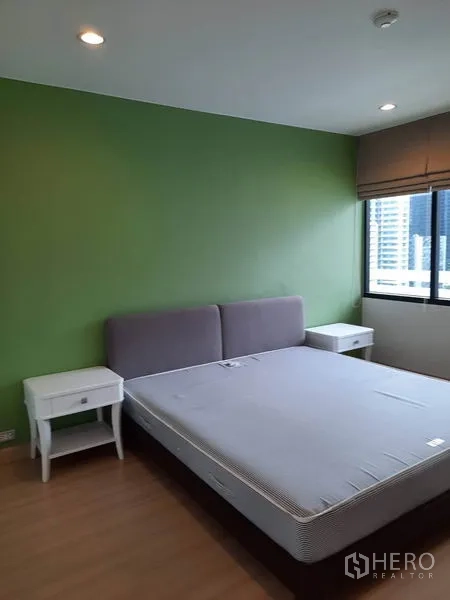 公寓 出租在Watthana, Bangkok - 第二卧室绿色特色墙，大床、临窗观景与床头柜。