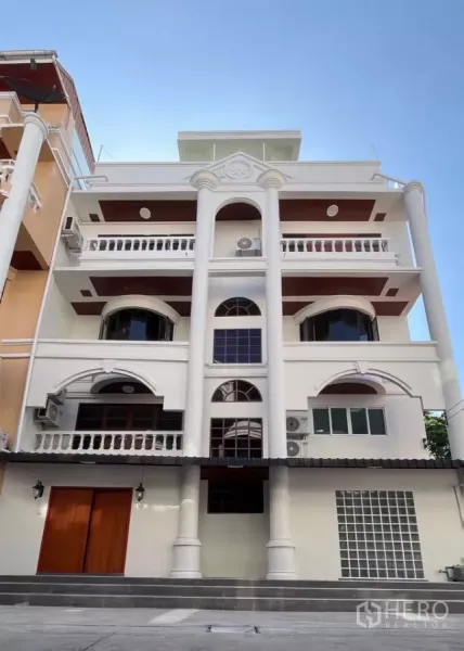 Home Office for rent in Watthana, Bangkok - Five-storey classic-meets-modern home office facade with columns and balconies in Watthana, Bangkok, under a blue sky.