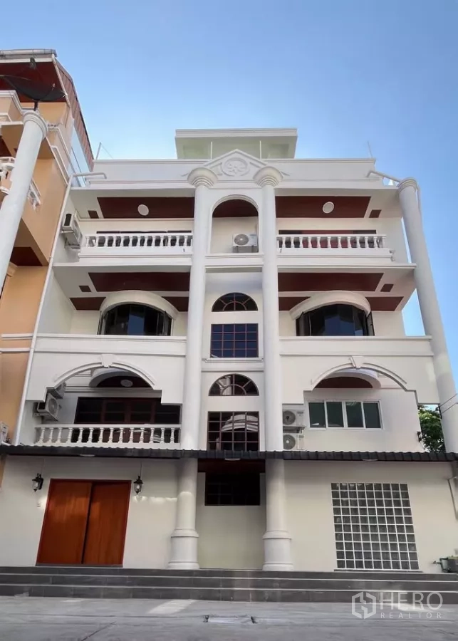 Home Office for rent in Watthana, Bangkok - Five-storey classic-meets-modern home office facade with columns and balconies in Watthana, Bangkok, under a blue sky.