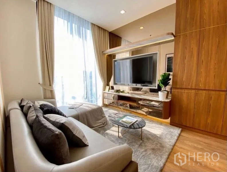 คอนโด ให้เช่าในWatthana, Bangkok - ห้องนั่งเล่นรับแสงธรรมชาติ หน้าต่างสูงจรดเพดาน ทีวีติดผนังและชั้นวางบิลท์อิน