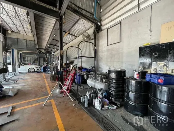 货栈 出租在Lat Phrao, Bangkok - 仓库内部，钢结构挑高屋顶、卷帘门与沿墙储物油桶