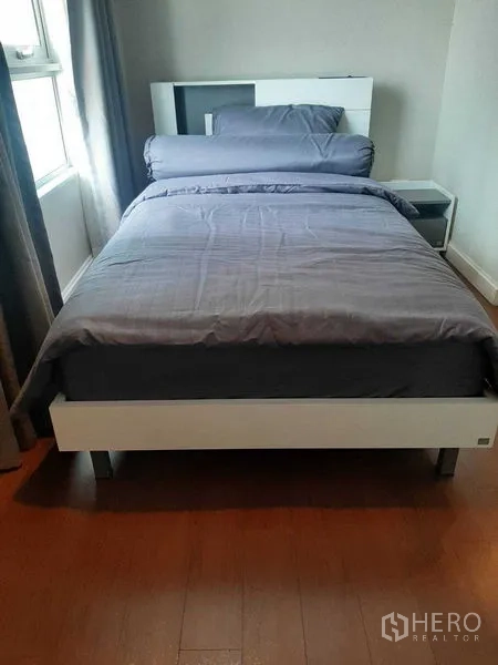 Condominium for rent or sale in Huai Khwang, Bangkok - Compact bedroom with single bed, bedside table, and window.