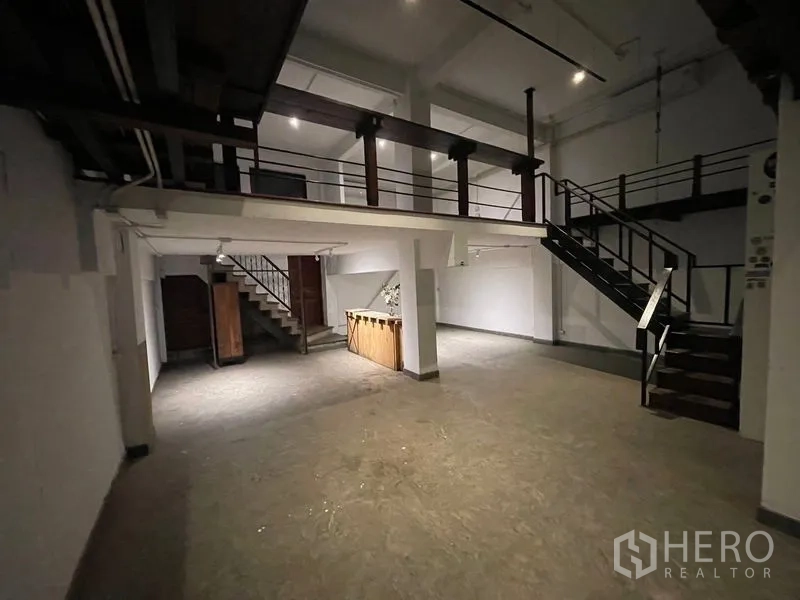 店屋 出租在Suan Luang, Bangkok - 挑高空间带夹层步道与开放楼梯，白墙与工业风栏杆。