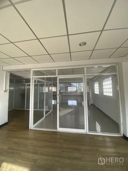 Office Space for rent in Khlong Toei, Bangkok - Glass-partitioned meeting room with double doors beside wood-look flooring in the office area.