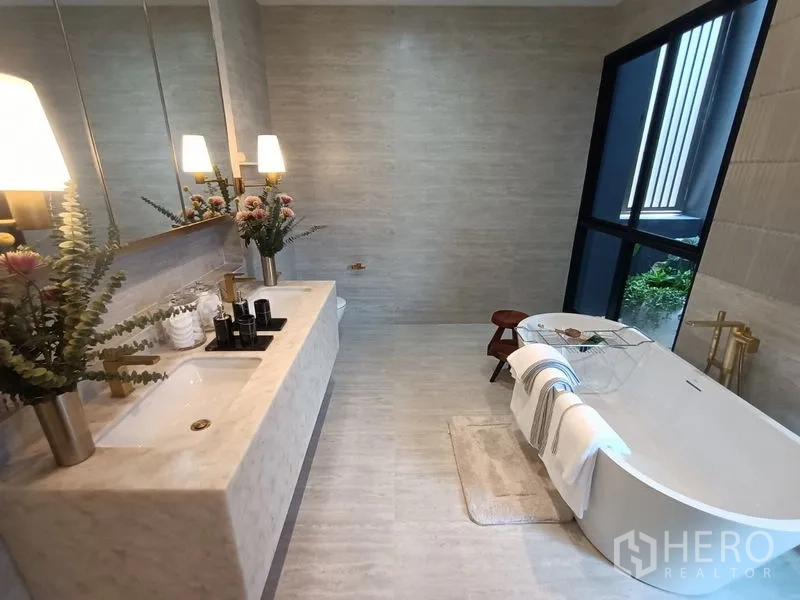 บ้าน ขาย - ห้องน้ำหรู เคาน์เตอร์หินอ่อน อ่างแช่ตัวติดหน้าต่างบานใหญ่และต้นไม้เขียว