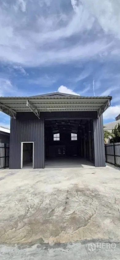 Warehouse for rent in Lat Phrao, Bangkok - Front exterior of a steel warehouse with wide covered entrance and concrete forecourt.
