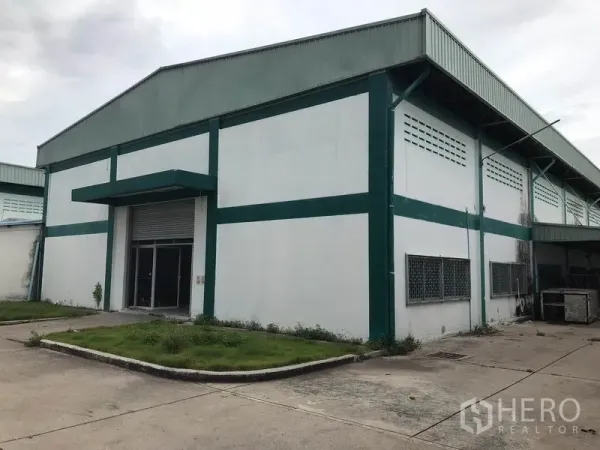 โรงงาน ให้เช่าในMueang Chon Buri, Chon Buri - อาคารโรงงานสีขาว-เขียวพร้อมประตูม้วนและลานคอนกรีตในนิคมอุตสาหกรรม