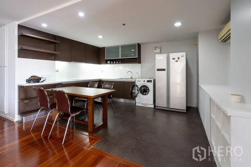 公寓 出售在Watthana, Bangkok - 开放式厨房配餐桌、深色橱柜、双开门冰箱与滚筒洗衣机。