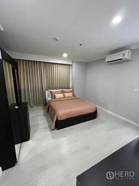 Condominium for sale in Sathon, Bangkok - Second bedroom with double bed, wall-mounted air conditioner, and floor-to-ceiling drapes.