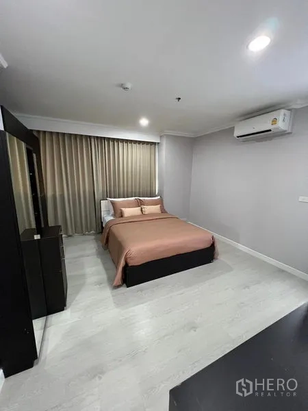 Condominium for sale in Sathon, Bangkok - Second bedroom with double bed, wall-mounted air conditioner, and floor-to-ceiling drapes.